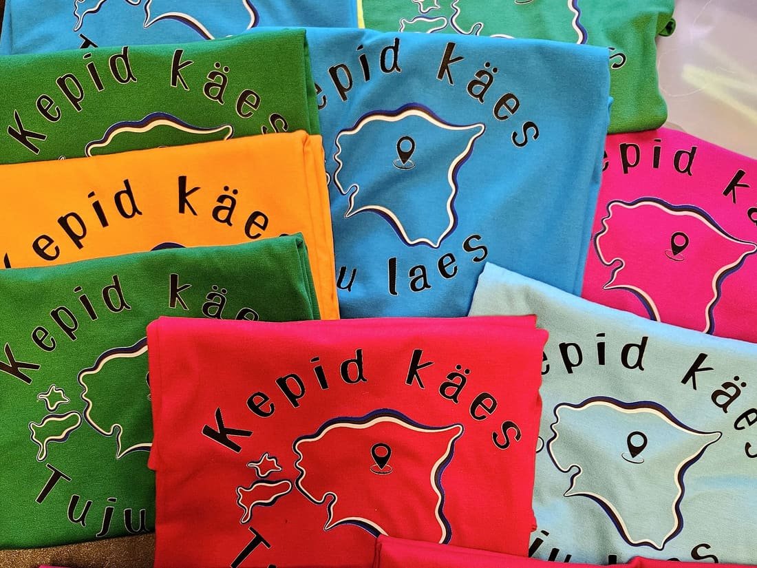 A pile of colourful T-shirts, all with the same DTF print